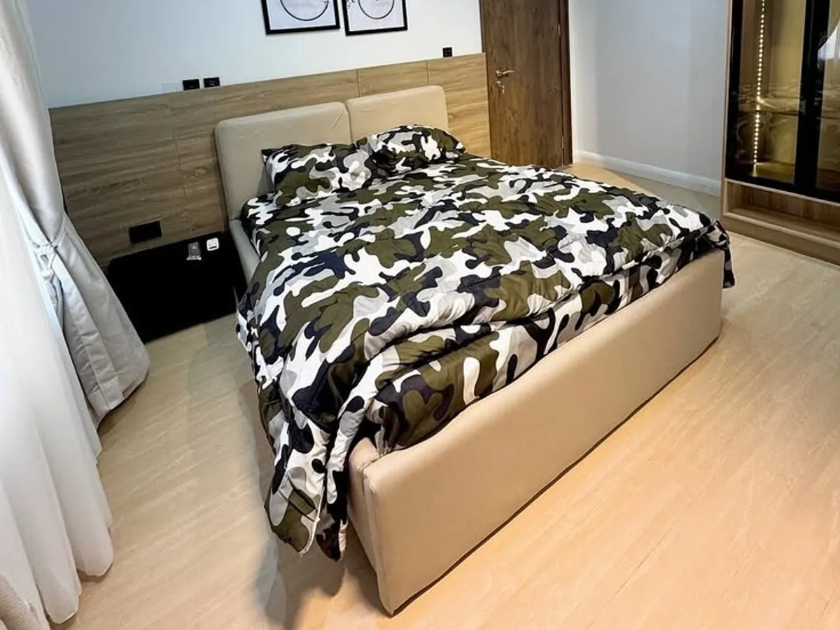 A student bedroom with a wooden headboard, double bed and soft neutral walls