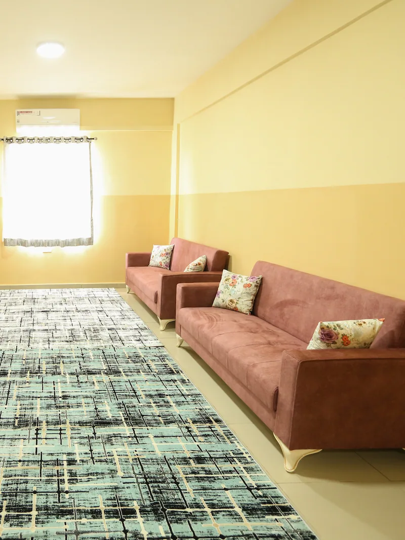 A bright student sitting room with two sofas and a patterned rug